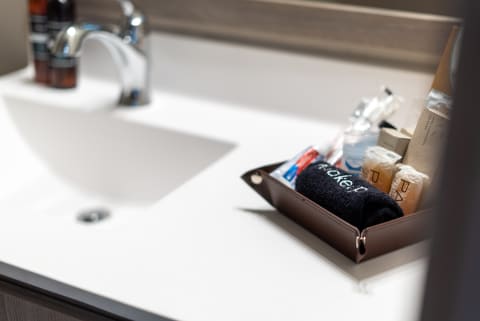A contemporary bathroom sink with a leather tray filled with toiletries and a towel.