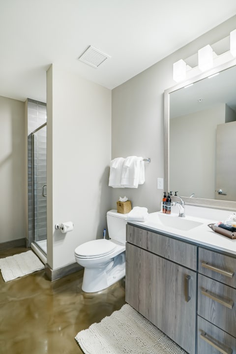 A contemporary bathroom showcasing a glass shower, white vanity, and polished flooring.