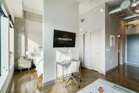 Interior view of a stylish studio apartment featuring a bed, desk, and modern design elements.