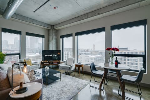 Modern urban apartment with large windows, stylish furniture, and city views.