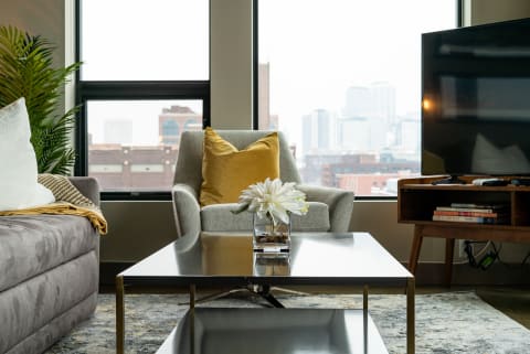 Cozy living room with a coffee table, armchair, sofa, and city skyline view.