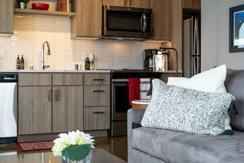 Cozy modern kitchen with sleek cabinets and plush sofa in a living area.