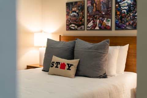 Cozy bedroom with gray pillows and urban themed artwork.