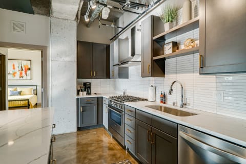 Modern kitchen with dark cabinets, white subway tile, and a glimpse of an adjacent bedroom.