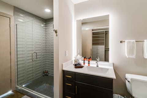 Modern bathroom with glass shower enclosure, dark vanity, and neutral colors.