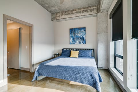 Contemporary bedroom with a blue quilted bed and abstract artwork on the wall.