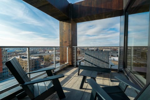 A balcony with dark wooden chairs and a view of the city below.