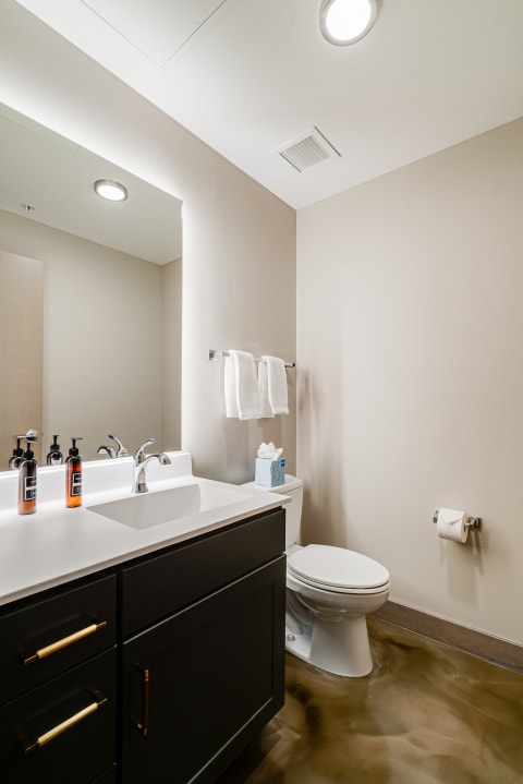 Modern bathroom featuring a white vanity, towels, and a polished floor.