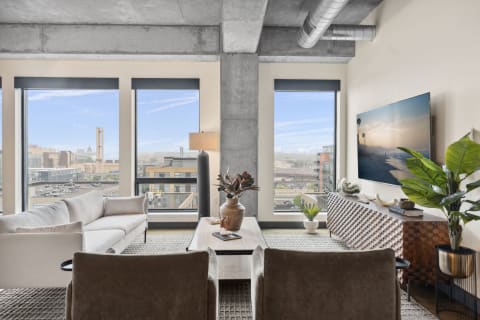 A stylish living room featuring large windows, modern furniture, and a city skyline view.