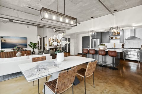 Open-concept apartment with a dining table, kitchen, and living area, showcasing modern design elements.