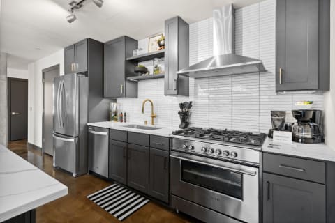 Contemporary kitchen featuring dark cabinets, stainless steel appliances, and a white countertop.