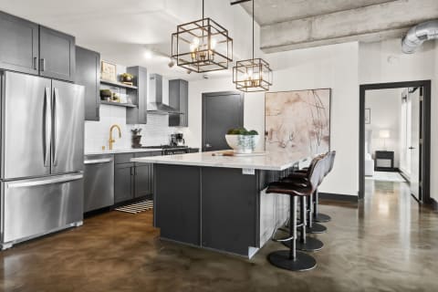 Modern kitchen with dark gray cabinets, stainless steel appliances, and a marble countertop island.
