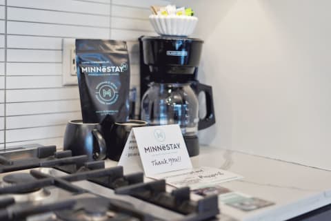 A coffee station with MINNESTAY coffee, a coffee maker, and a thank you note in a modern kitchen.
