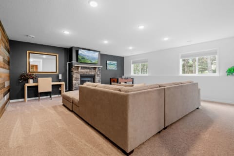 Cozy living room featuring a beige sectional couch, stone fireplace, and a foosball table.