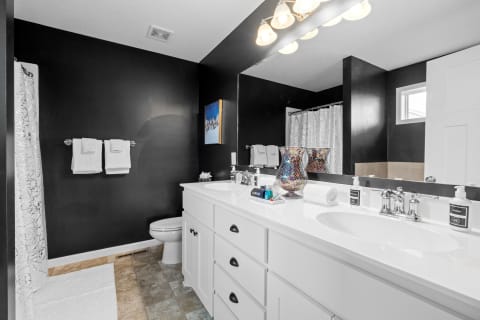 Stylish bathroom with black walls, white vanity, and elegant decor.