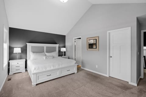Modern bedroom featuring a white bed, gray walls, and stylish furnishings.