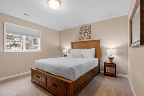 A well-decorated bedroom featuring a wooden bed, white bedding, and a window with natural light.