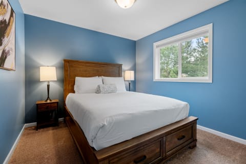 A cozy bedroom featuring a wooden bed, blue walls, and soft lighting.