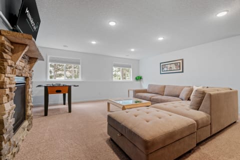 Cozy living room with sectional couch, stone fireplace, and foosball table.