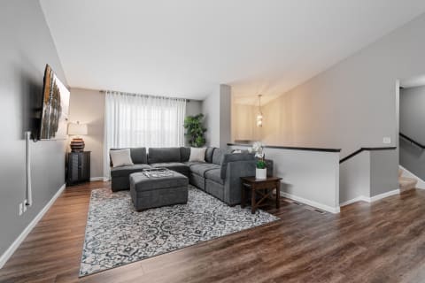 Modern living room featuring a grey sectional sofa, hardwood floors, and a large window.