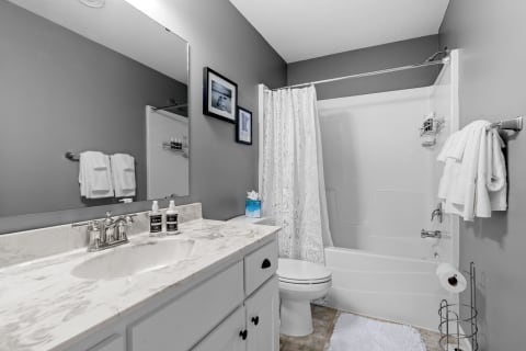 A clean and modern bathroom featuring a marble countertop and a floral shower curtain.