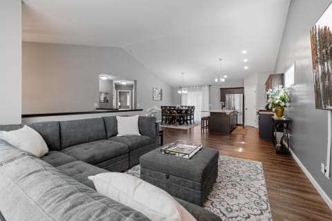 Open-concept living area featuring a grey sectional sofa and a dining area in the background.