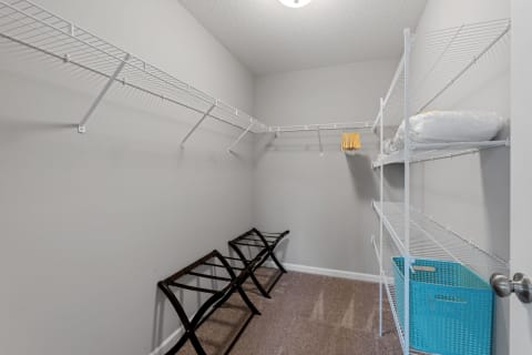 Interior view of a spacious closet with wire shelves and folding racks.
