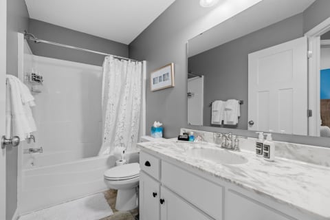 Modern bathroom with gray walls, marble countertop, and floral shower curtain.