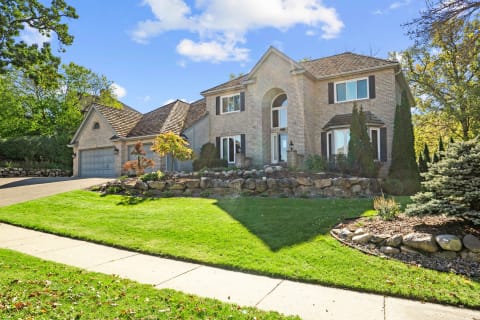 Exterior view of a suburban house with brick facade and landscaped garden.