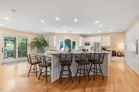 Spacious kitchen with hardwood floors, white cabinets, and a central island with seating.