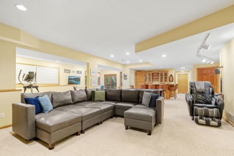 Cozy basement living room featuring a sectional sofa, massage chair, and a wet bar.