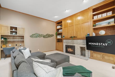 Cozy living room with gray sectional sofa, stone fireplace, and stylish wall art.