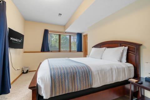 Cozy bedroom featuring a queen-sized bed, television, and natural light from the window.