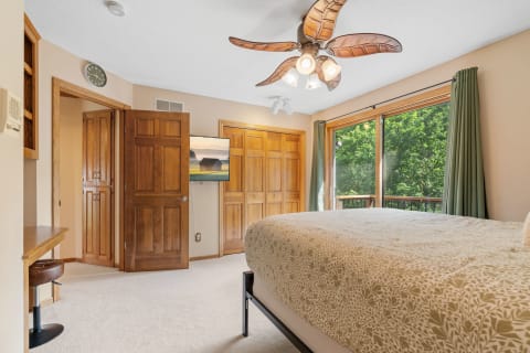 Cozy bedroom featuring a large window, comfortable bed, and wooden accents.