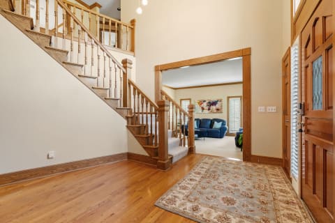 Interior view showing a wooden staircase and a cozy living room with blue chairs.