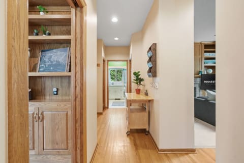 Cozy hallway with built-in shelves, wooden table, and a glimpse of the kitchen and living area.