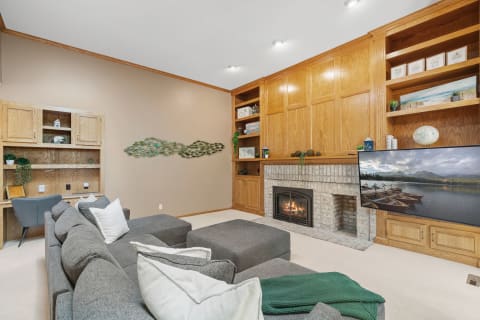 A gray sectional sofa in a cozy living room with a fireplace and a mounted TV.