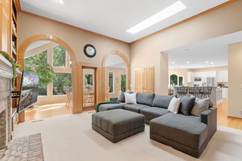 Living room featuring a gray sectional couch, arched windows, and a view of the dining area.