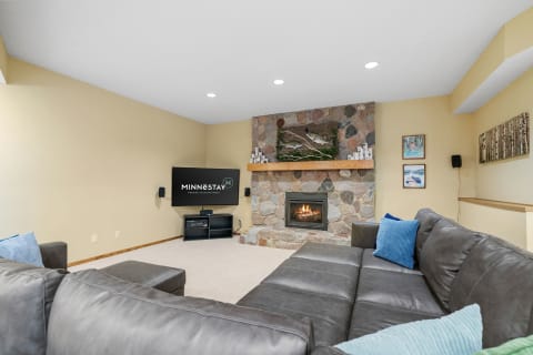 Cozy living room with leather sectional, stone fireplace, and mounted television.