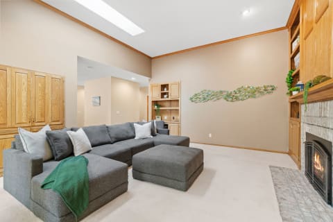 A spacious living room featuring a gray sectional sofa, fireplace, and artistic wall decor.