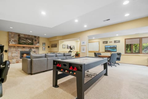 Spacious basement with sectional sofa, fireplace, and air hockey table.