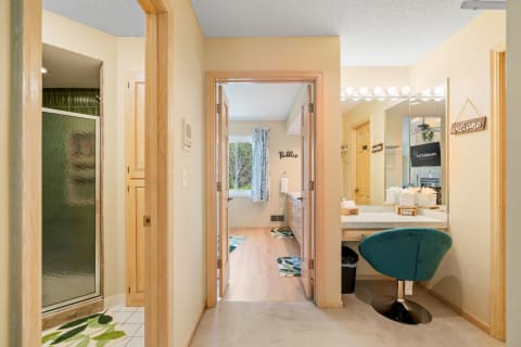 Bathroom corridor with a shower, vanity area, and natural light from a window.