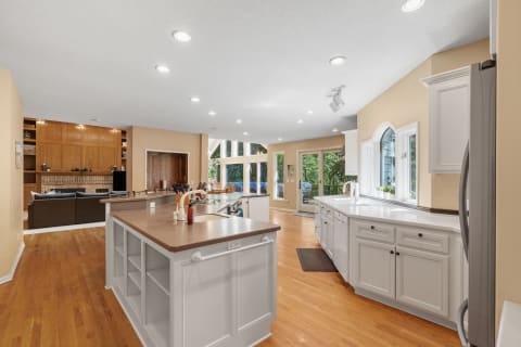 Spacious kitchen with white cabinets, large island, and natural light from windows.