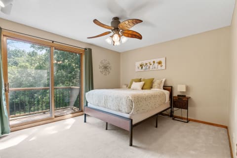 Cozy bedroom featuring a large bed, decorative pillows, and a sliding glass door leading to a balcony.