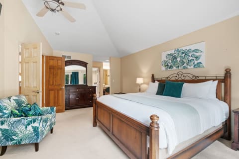 A stylish bedroom featuring a wooden bed, tropical armchair, and warm decor.
