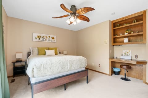 Cozy bedroom with a bed, bedside tables, and a workspace with a desk and chair.