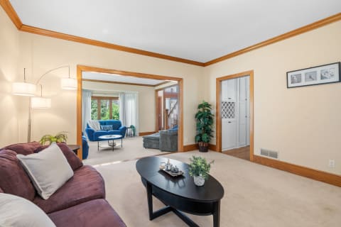 A spacious living room featuring a burgundy sofa, blue couch in the background, and a modern lamp.