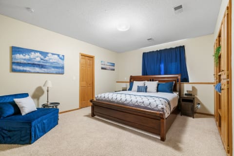 A comfortable bedroom featuring a wooden bed, blue cushions, and decorative artwork.