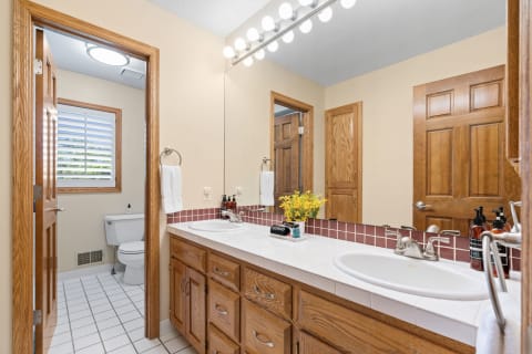 A well-lit bathroom featuring a double vanity and wooden cabinetry.