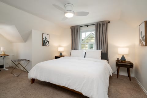 Cozy attic bedroom featuring a king-sized bed, stylish nightstands, and natural light.